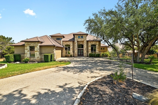 view of front of house with metal roof, stone siding, concrete driveway, stucco siding, and a standing seam roof