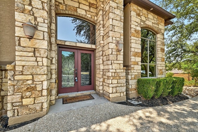 view of exterior entry featuring stone siding and french doors