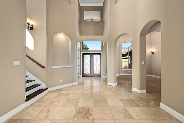 entrance foyer with arched walkways, french doors, and baseboards