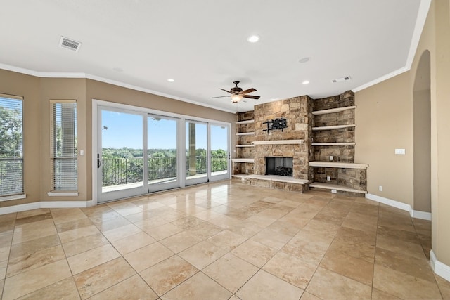 unfurnished living room featuring baseboards, visible vents, arched walkways, ornamental molding, and a stone fireplace