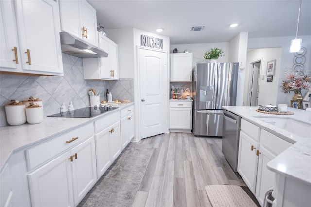 kitchen featuring light stone counters, light hardwood / wood-style flooring, backsplash, white cabinetry, and appliances with stainless steel finishes