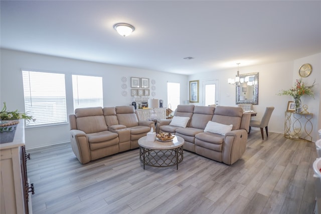 living room featuring a wealth of natural light, an inviting chandelier, and light hardwood / wood-style flooring