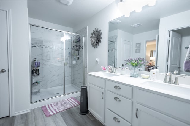 bathroom featuring an enclosed shower, hardwood / wood-style flooring, and dual bowl vanity