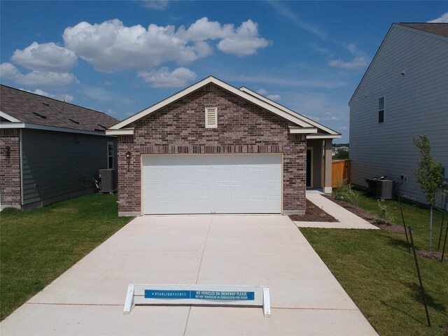 view of front of house with a garage, a front yard, and central air condition unit