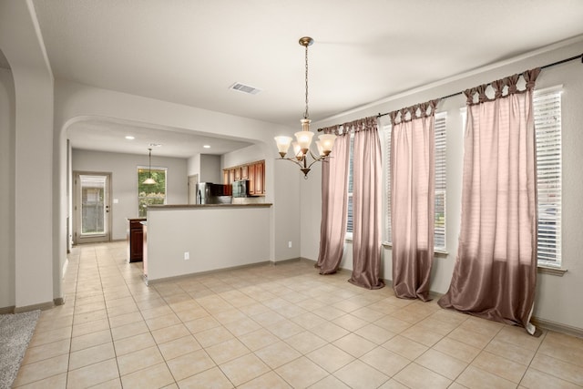 tiled empty room with an inviting chandelier