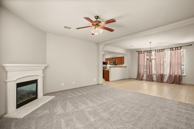 unfurnished living room featuring ceiling fan with notable chandelier and light colored carpet