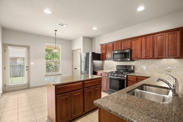 kitchen featuring pendant lighting, light tile patterned flooring, sink, a kitchen island, and stainless steel appliances