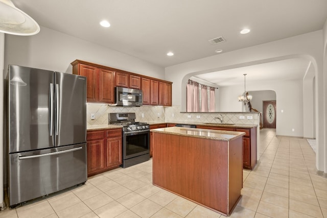 kitchen featuring sink, stainless steel appliances, backsplash, a chandelier, and decorative light fixtures