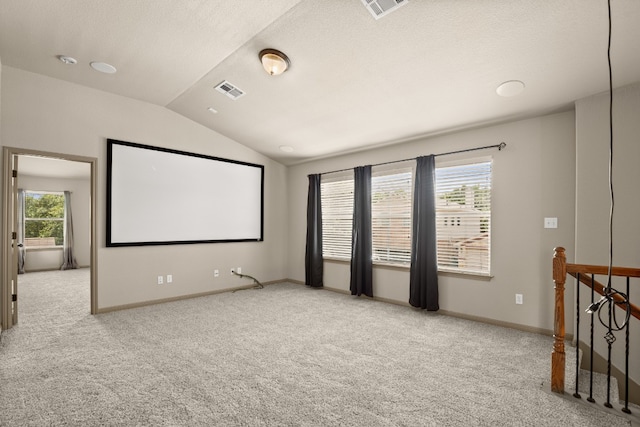 carpeted home theater room with vaulted ceiling and a healthy amount of sunlight