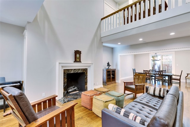 living room with a high ceiling, a fireplace, and light hardwood / wood-style flooring