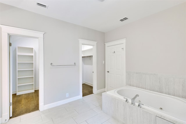 bathroom with wood-type flooring and a relaxing tiled tub