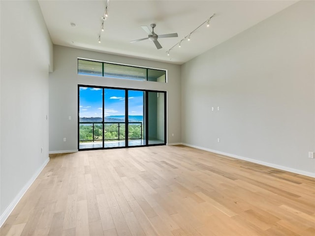 empty room with ceiling fan, rail lighting, and light hardwood / wood-style flooring