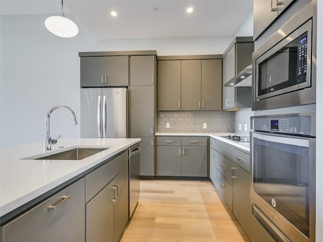 kitchen featuring backsplash, stainless steel appliances, gray cabinetry, and sink