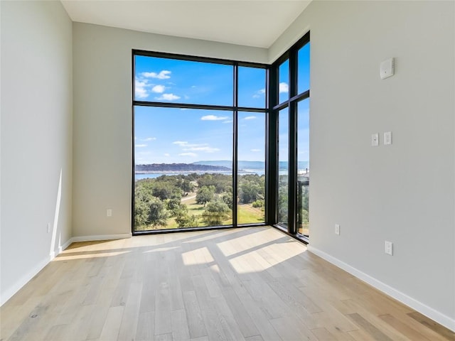 spare room with a water view and light hardwood / wood-style flooring