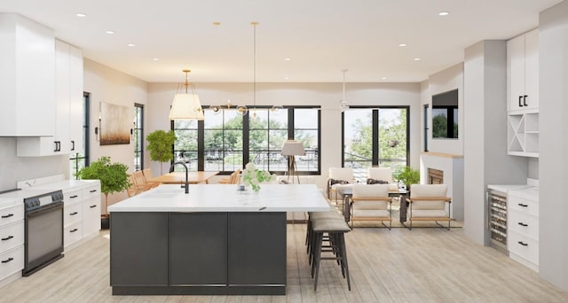 kitchen with white cabinetry, a kitchen island with sink, oven, and decorative light fixtures