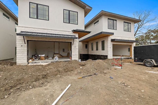 rear view of property featuring an attached garage and stucco siding