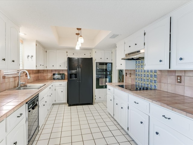 kitchen with white cabinetry, tile countertops, black appliances, a tray ceiling, and sink