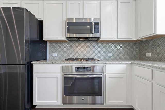 kitchen featuring white cabinetry, tasteful backsplash, light stone counters, and stainless steel appliances