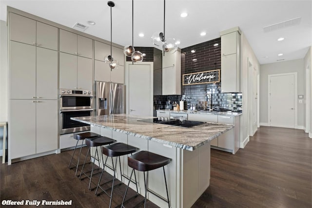 kitchen featuring a large island, hanging light fixtures, stainless steel appliances, tasteful backsplash, and dark hardwood / wood-style flooring