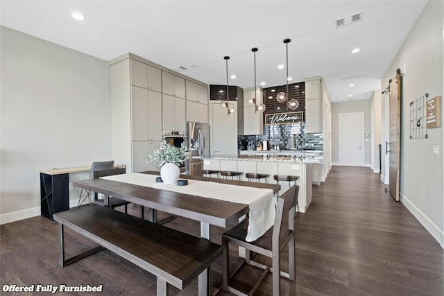 dining room with a barn door and dark hardwood / wood-style flooring