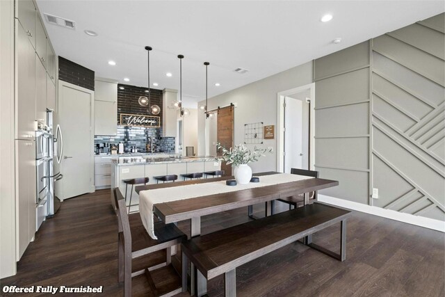 dining area featuring a barn door and dark hardwood / wood-style flooring