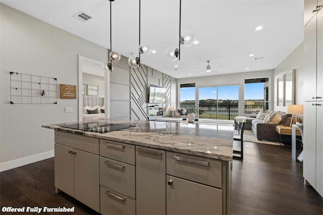 kitchen with black electric stovetop, decorative light fixtures, light stone counters, and dark wood-type flooring