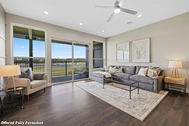 living room featuring dark hardwood / wood-style floors, ceiling fan, and a water view