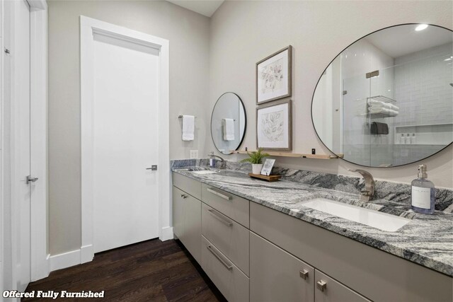 bathroom with wood-type flooring, vanity, and a shower with door