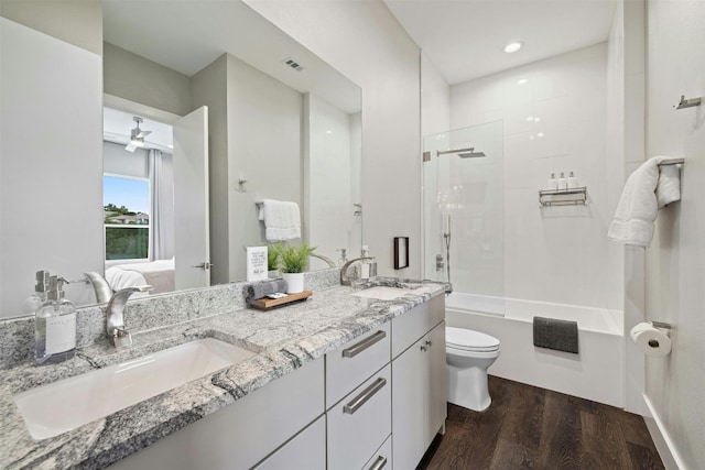 full bath with double vanity, wood finished floors, a sink, and toilet