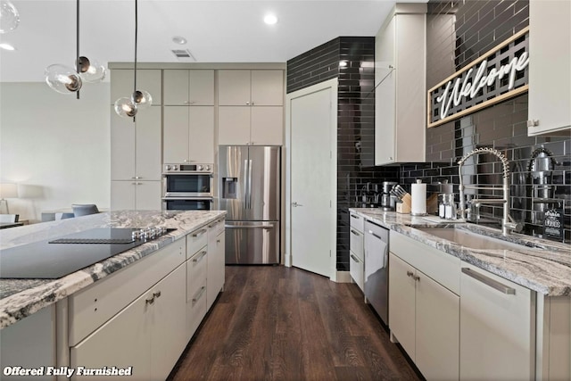 kitchen with decorative backsplash, light stone counters, appliances with stainless steel finishes, dark wood-style flooring, and a sink