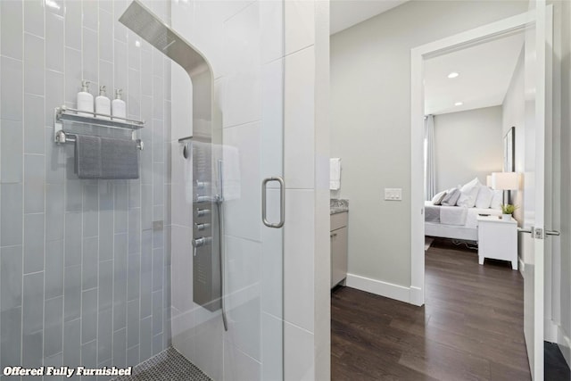 bathroom featuring wood finished floors, vanity, baseboards, a shower stall, and ensuite bath