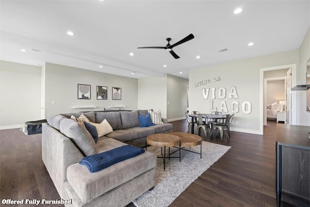 living room featuring ceiling fan and dark wood-type flooring