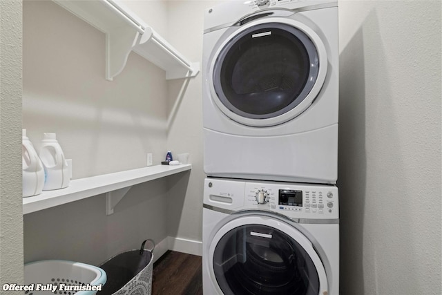 laundry area with dark hardwood / wood-style flooring and stacked washer / dryer