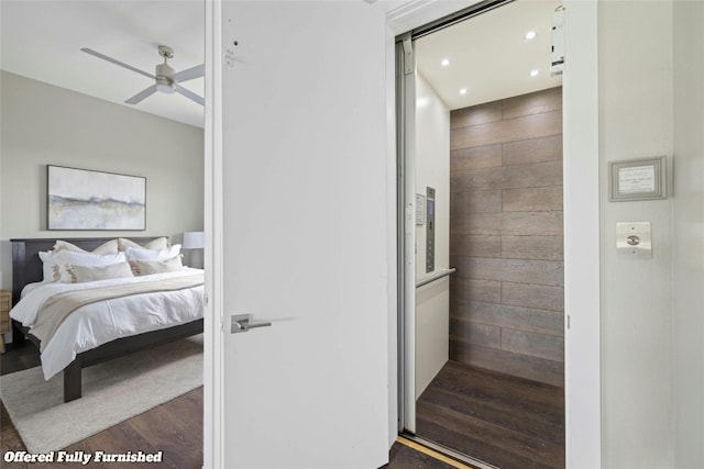 bedroom featuring dark wood-type flooring, wood walls, recessed lighting, and elevator