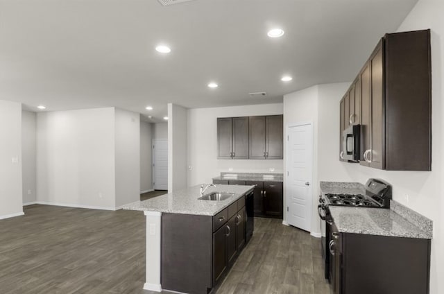 kitchen with sink, dark wood-type flooring, a kitchen island with sink, light stone counters, and range with gas stovetop