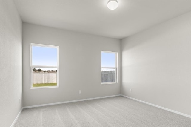 empty room featuring light carpet and baseboards