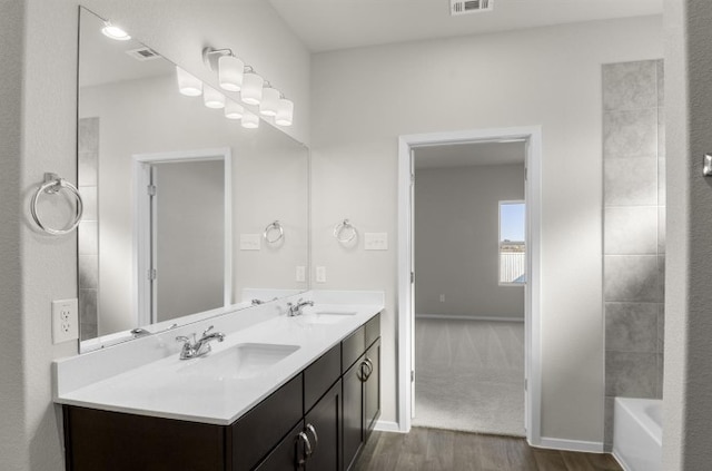 full bathroom featuring double vanity, wood finished floors, visible vents, and a sink