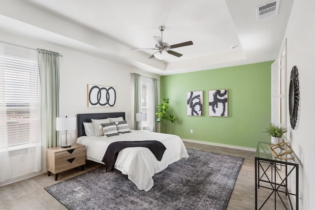 1837 Flying Horseshoe Bnd, Georgetown, TX 78628 - bedroom featuring a tray ceiling, wood finished floors, ceiling fan, and baseboards