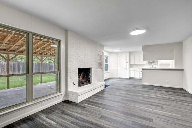 unfurnished living room featuring dark hardwood / wood-style floors and a brick fireplace