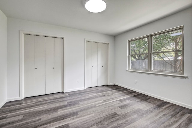 unfurnished bedroom featuring multiple closets and light hardwood / wood-style floors