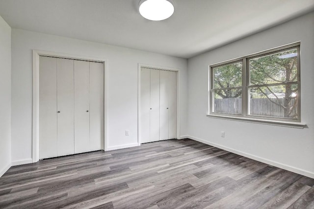 1504 Colony Creek Dr, Austin, TX 78758 - unfurnished bedroom with baseboards, wood finished floors, and multiple closets
