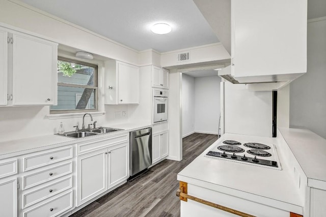 kitchen with dark wood finished floors, visible vents, white cabinetry, a sink, and white appliances