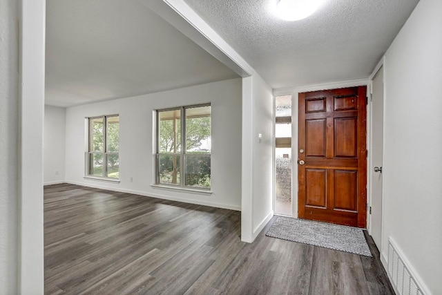 foyer with dark wood-style floors, visible vents, a textured ceiling, and baseboards