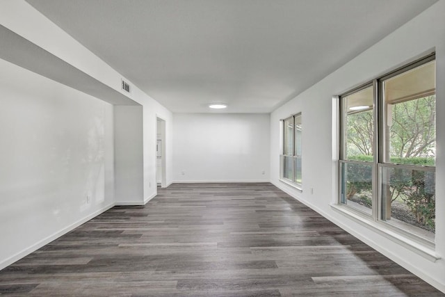 unfurnished room featuring visible vents, baseboards, and dark wood-type flooring