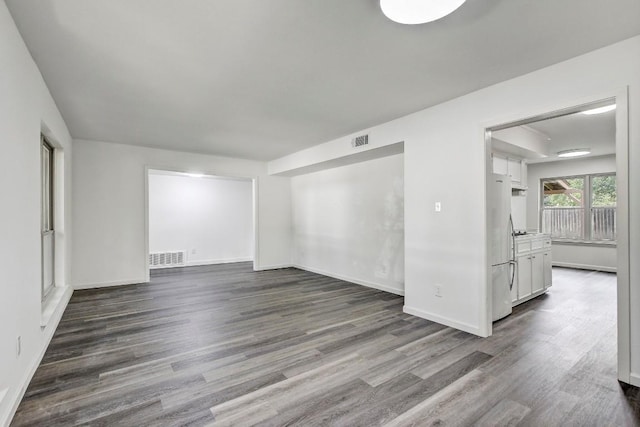 unfurnished room with dark wood-type flooring, visible vents, and baseboards