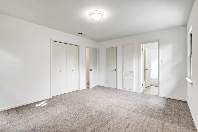 unfurnished bedroom with carpet floors, a closet, visible vents, and baseboards