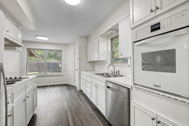 kitchen with white appliances, white cabinets, sink, dark hardwood / wood-style floors, and a textured ceiling