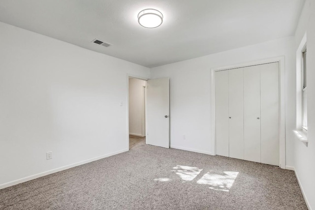 unfurnished bedroom featuring a closet, baseboards, visible vents, and carpet flooring