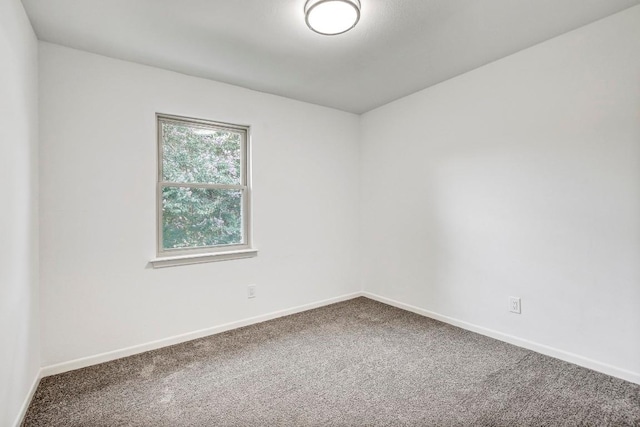 carpeted empty room featuring baseboards