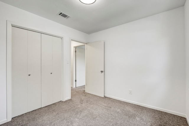 unfurnished bedroom featuring a closet and light colored carpet